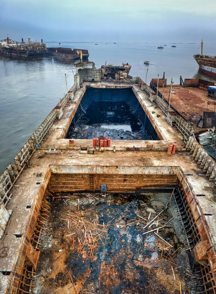 From above of aged rusty damaged ship floating on calm water of ocean in cloudy day